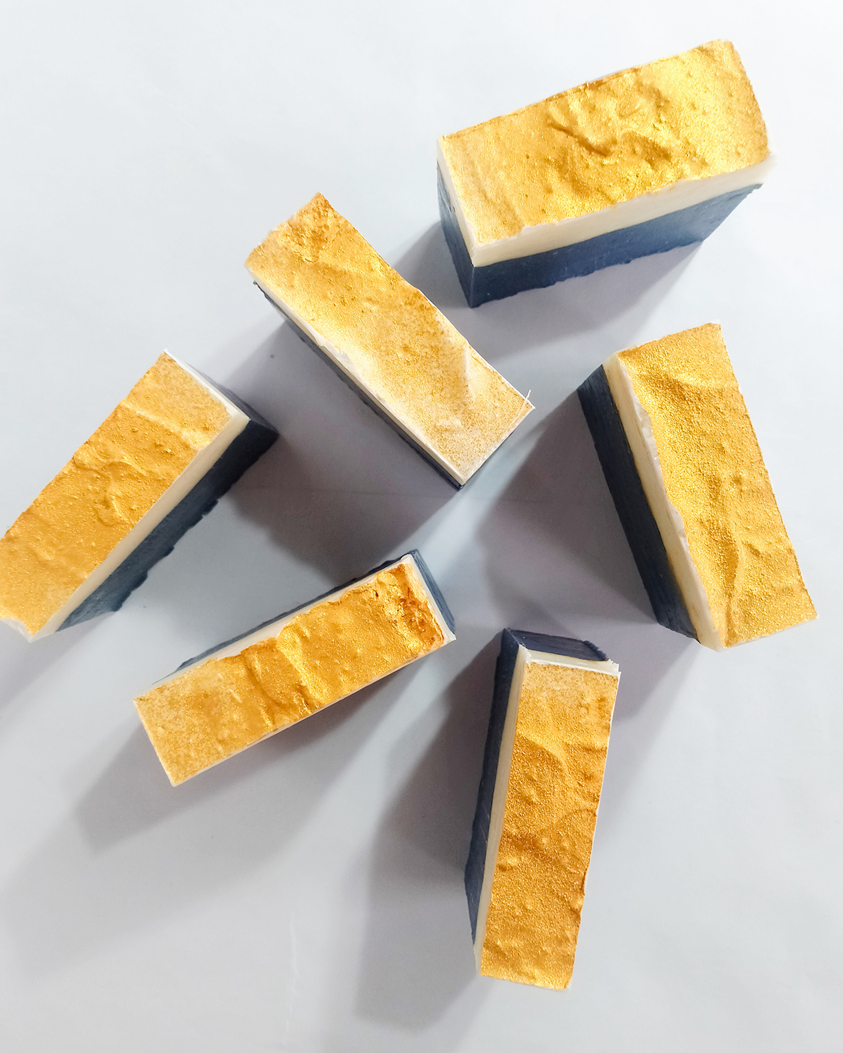 Dvojfarebné mydlo s laktátom sodným na bielom pozadí stojí v niekoľkých kusoch postavené a odfotené zvrchu.